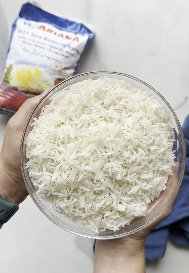 a beautiful bowl of afghan white rice basmati sela rice perfectly cooked with Ariana sweets inc in the background